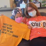 Sarah and Meghan Smith pictured seated on a couch holding up a shirt